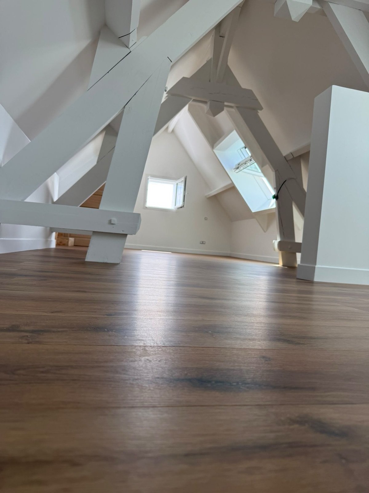 Combles lumineux : charpente blanche et parquet