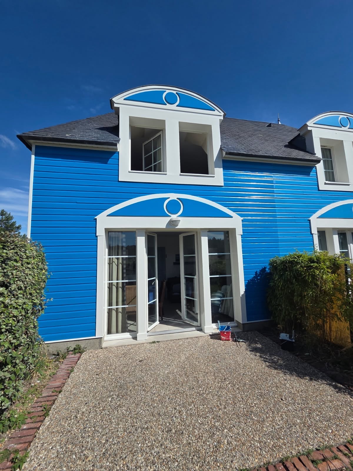 Villa repeinte en bleu, grandes fenêtres blanches